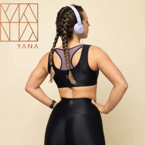 Yana Active, woman wearing black activewear leggings and crop top with a pair of headphones pictured from behind,