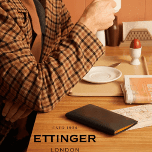 ettinger luxury wallets, man in luxury jacket sitting at table drinking tea with ettinger wallet